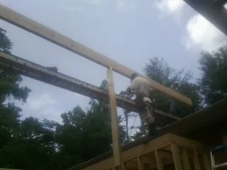 Carpenter setting a ridge beam over a new addition frame — Ice Dam Removal by Roofing Brothers in Lattimore