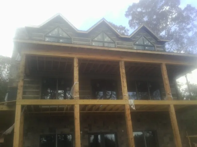 Dormers and porch framing on a large log home under construction — Roof Coating work by our crew in Lattimore