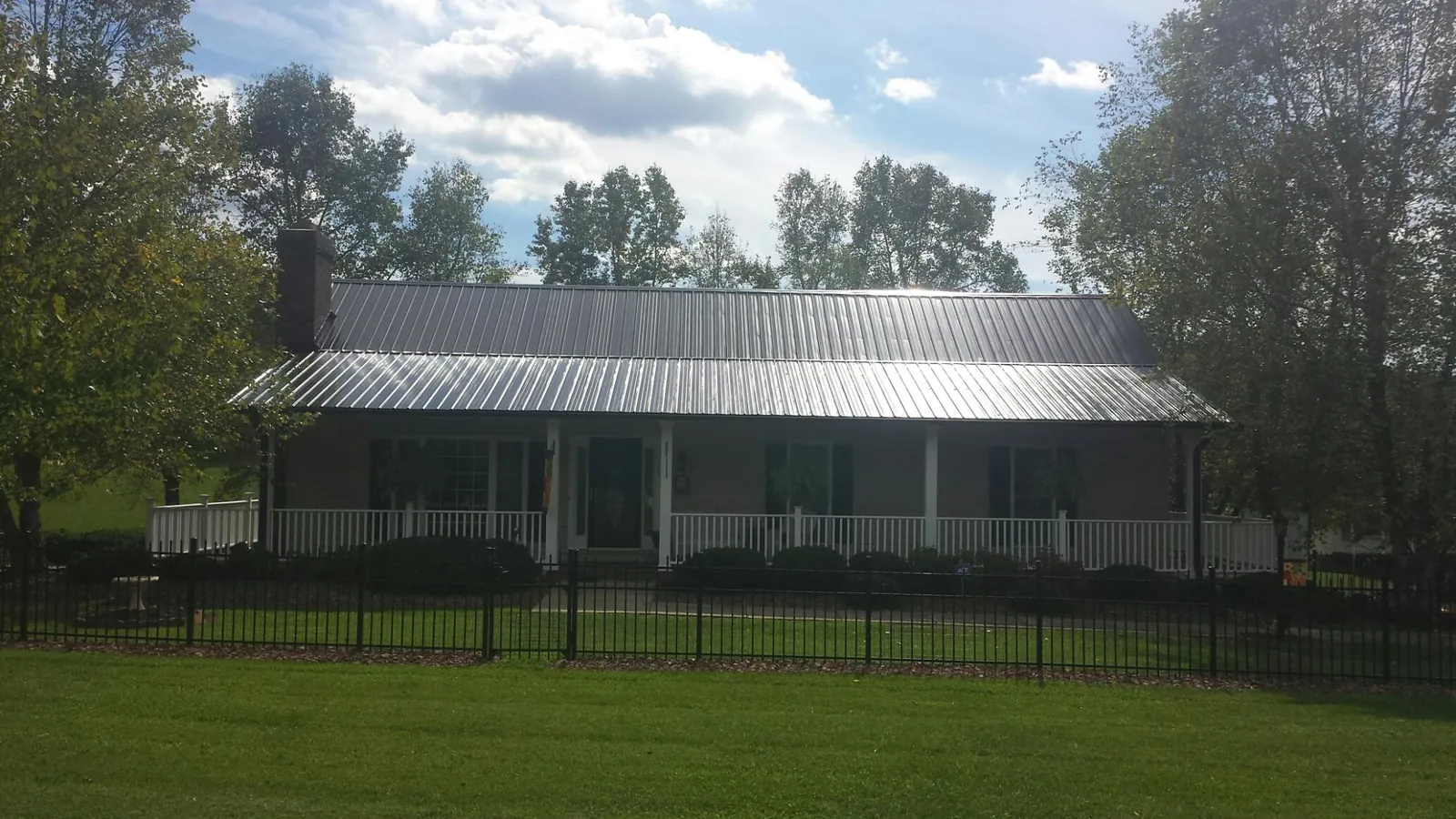 Gray metal roof on a brick ranch with a full width front porch — Gutter Guard Installation work by our crew in Lattimore