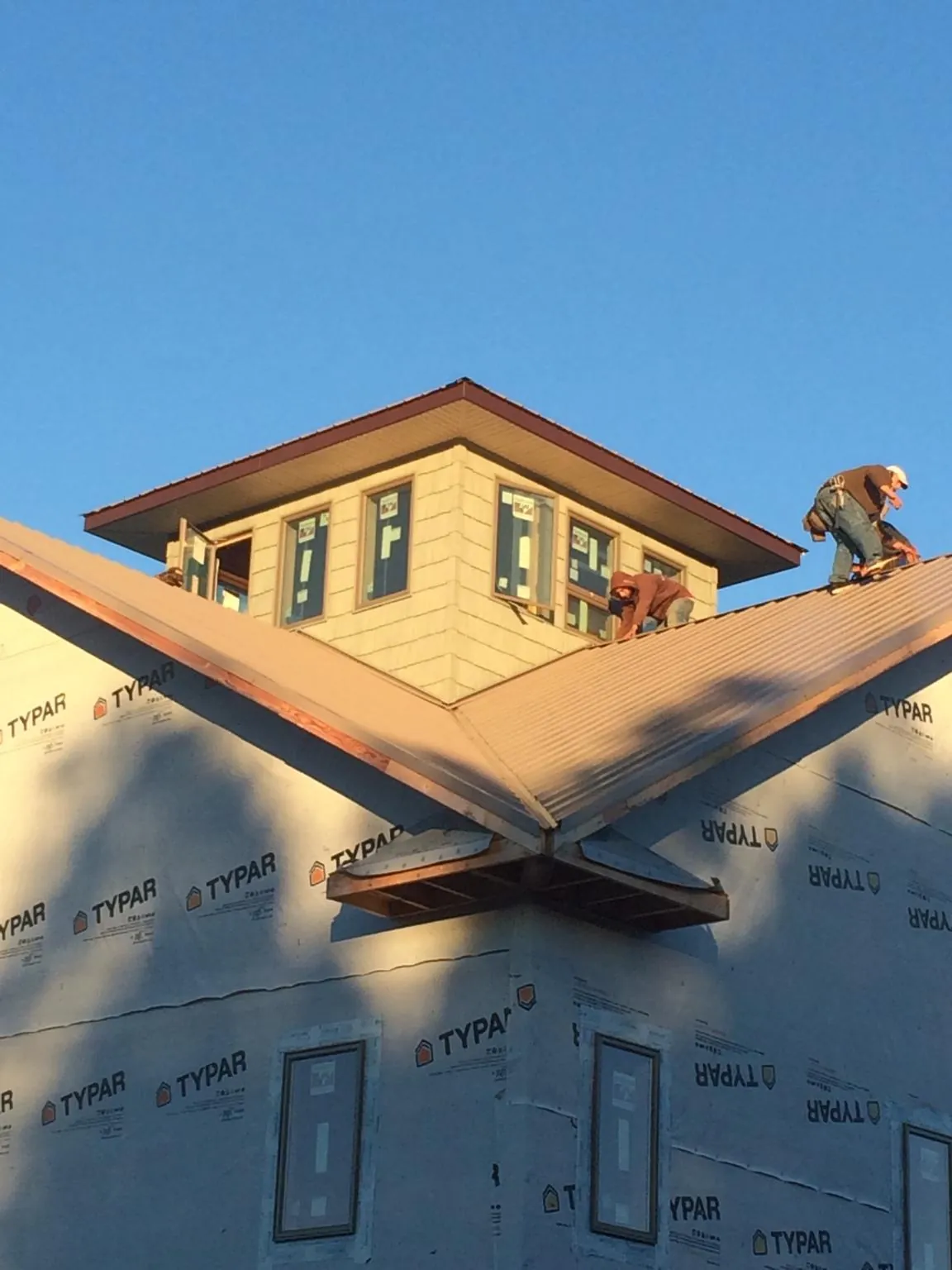 Roofers working around a rooftop cupola on a new metal roof at sunset — Roof Waterproofing in Lattimore by Roofing Brothers